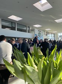 Innenaufnahme des Autohauses mit vielen Gästen, die an schwarzen Tischen sitzen. Im Vordergrund unscharfe Tulpen, im Hintergrund große Fenster und das Skoda-Logo. (Foto: Autohaus Peter)