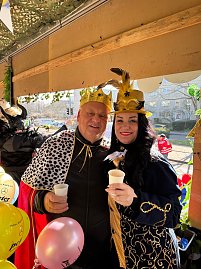 Helmut Peter und Christina Dost, verkleidet mit goldenen Kronen und prächtigen Umhängen, halten jeweils einen weißen Becher und lächeln in die Kamera. Bunte Luftballons im Vordergrund. (Foto: Autohaus Peter GmbH)