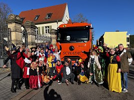 "Gruppe von kostümierten Menschen in Märchen- und Tierverkleidungen posiert vor einem orangefarbenen LKW mit der Aufschrift SCHADE. (Foto: Autohaus Peter GmbH)