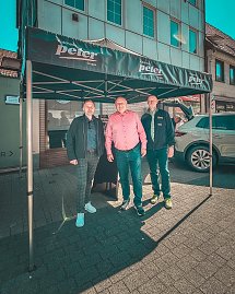 Drei Männer, darunter Geschäftsführer Helmut Peter, stehen unter einem schwarzen Pavillon mit „Autohaus Peter“-Logo in der Innenstadt. (Foto: Autohaus Peter)