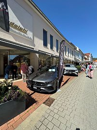 Zwei Mercedes-Ausstellungswagen, einer in Grau, einer in Silber, stehen vor einem Modegeschäft, Passanten schlendern vorbei. (Foto: Autohaus Peter)