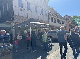 Menschen unterhalten sich unter einem schwarzen „Autohaus Peter“-Pavillon, daneben ein graues Ausstellungsfahrzeug. (Foto: Autohaus Peter)