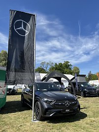 Mercedes-Benz SUV mit Flagge: Grauer Mercedes-Benz SUV vor schwarzer Mercedes-Flagge und Pavillon, weitere Fahrzeuge im Hintergrund. (Foto: Autohaus Peter GmbH)