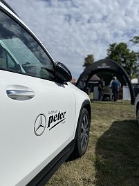 Weißer Mercedes-Benz mit Logo: Seitliche Nahaufnahme eines weißen Mercedes-Benz mit Autohaus-Peter-Logo, im Hintergrund der Messestand. (Foto: Autohaus Peter GmbH)