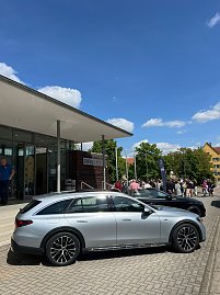  Vor der Stadthalle Wittenberg steht ein silberner Mercedes-Benz Kombi. Im Hintergrund sind weitere Autos, Menschen und eine Mercedes-Fahne zu sehen. (Foto: Autohaus Peter)
