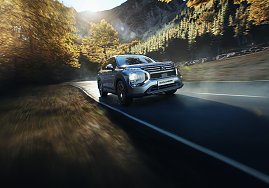 Fahrt durch die Berge: Silberner Mitsubishi Outlander fährt dynamisch auf einer kurvigen Bergstraße, umgeben von herbstlich gefärbten Bäumen. (Foto: Mitsubishi Motors)