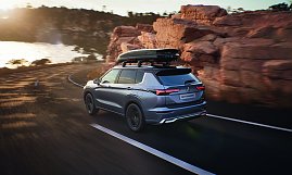 Mit Dachbox: Mitsubishi Outlander von hinten auf einer Küstenstraße, mit montierter Dachbox, umgeben von Felsen und Blick auf das Meer. (Foto: Mitsubishi Motors)