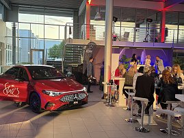 Roter Mercedes-Benz CLA 250+ steht in einer Veranstaltungshalle, im Hintergrund sitzen Gäste an Stehtischen. Mercedes-Benz CLA 250+ mit EQ-Technologie | Energieverbrauch kombiniert: 14,1-12,2 kWh/100 km | CO2Emissionen kombiniert: 0 g/km | CO2-Emissionsklasse: A (Foto: Eric Freytag)