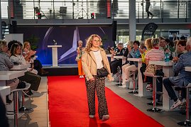 Eine Frau mit lockigem, blondem Haar, beiger Jacke, weißem Oberteil, Leopardenmuster-Hose und kleiner schwarzer Umhängetasche läuft über den roten Teppich. (Foto: Eric Freytag)