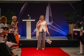 Eine blonde Frau mit Brille, ärmellosem cremefarbenem Oberteil, gemusterten Hosen und passender Handtasche präsentiert sich am Ende des roten Teppichs. (Foto: Eric Freytag)