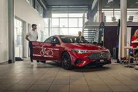 Roter Mercedes-Benz CLA 250+ mit Aufschrift „Shes Mercedes“ auf der Fahrertür, zwei Männer stehen daneben in einer Ausstellungshalle. Mercedes-Benz CLA 250+ mit EQ-Technologie | Energieverbrauch kombiniert: 14,1-12,2 kWh/100 km | CO2Emissionen kombiniert: 0 g/km | CO2-Emissionsklasse: A (Foto: Eric Freytag)