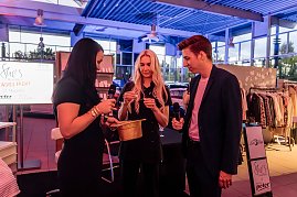 Drei Personen, darunter Christina Dost, ziehen Lose aus einem goldenen Hut, zwei halten Mikrofone, im Hintergrund ein Bildschirm mit „Shes Mercedes Ladies Night“ und Kleidungsständer. (Foto: Eric Freytag)