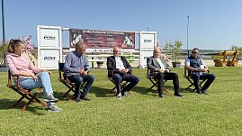 Fünf Personen sitzen auf Stühlen im Freien auf dem Reitplatz in Immenrode während der offiziellen Pressekonferenz zum Reitturnier 2025. Hinter ihnen ist ein großes Banner mit Informationen zum Turnier vom 18. bis 22. Juni zu sehen. Sonniges Wetter und grüne Rasenfläche prägen die Szene. (Foto: Depping/Autohaus Peter)