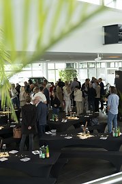 „Blick in den Ausstellungsraum des Autohauses Peter beim südafrikanischen Abend in Heiligenstadt. Zahlreiche Gäste stehen in Gruppen zusammen, unterhalten sich und genießen die entspannte Atmosphäre zwischen dekorierten Stehtischen und Fahrzeugen. (Foto: Peter Gruppe)