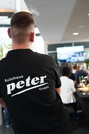 Ein Mitarbeiter der Autohaus Peter Gruppe mit Rückenansicht während des südafrikanischen Abends in Heiligenstadt, im Hintergrund sitzen Gäste an festlich gedeckten Tischen (Foto: Autohaus Peter Gruppe)