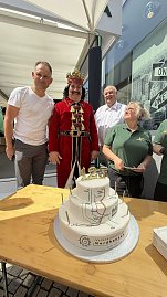 Helmut und Andreas Peter, der kostümierte Roland und eine Mitarbeiterin der Bäckerei stehen hinter der Jubiläumstorte (Foto: Autohaus Peter)
