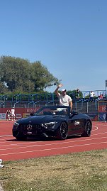 Ein schwarzes Mercedes-Benz Cabrio des Autohauses Peter fährt über die rote Laufbahn beim Leichtathletik-Meeting Anhalt 2025. Ein Sportler winkt den Zuschauern auf der Tribüne vom Cabrio aus zu. (Foto: Autohaus Peter )