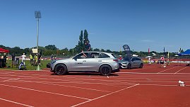 Einfahrt der Sportstars beim Leichtathletik-Meeting Anhalt 2025: Ein silberner Mercedes-Benz SUV des Autohauses Peter fährt über die rote Laufbahn, ein Sportler winkt aus dem geöffneten Schiebedach. Dahinter stehen weitere Fahrzeuge und Eventfahnen. (Foto: Autohaus Peter )