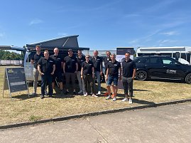 Gruppenfoto des Teams vom Autohaus Peter bei sonnigem Wetter. Zehn Personen stehen in schwarzer Teamkleidung mit Logo Peter nebeneinander vor einem silbernen Van und einem schwarzen Mercedes. Im Hintergrund sind ein Zelt, Werbebanner und weitere Fahrzeuge zu sehen. Alle lächeln in die Kamera. (Foto: Autohaus Peter )