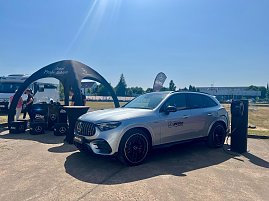 Ein silberner Mercedes-Benz SUV des Autohauses Peter steht während des Leichtathletik-Meetings Anhalt 2025 an einer mobilen Ladesäule. Links befindet sich ein schwarzes Promotion-Zelt mit dem Schriftzug Jetzt Probe fahren, daneben mehrere Boxen und Mitarbeiter des Autohauses. Im Hintergrund sind Wohnmobile, Bäume und ein sonniger, klarer Himmel zu sehen. (Foto: Autohaus Peter )