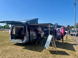 Auf dem Außengelände des Anhalt 2025 Leichtathletik-Meetings stehen mehrere Mercedes-Benz Fahrzeuge des Autohauses Peter, darunter ein silberner Campingbus mit geöffneten Türen und ausgefahrenem Aufstelldach. Menschen informieren sich an Infoständen unter Sonnenschein, während im Hintergrund weitere Fahrzeuge und Besucher zu sehen sind. (Foto: Autohaus Peter )