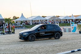 Ein schwarzer Mercedes-Benz SUV fährt über den Sandplatz einer Reitanlage am Abend. Im Hintergrund sitzen Zuschauer unter weißen Eventzelten und verfolgen das Turniergeschehen. [Mercedes-AMG GLA 35 4MATIC | Energieverbrauch kombiniert: 9,3-8,8 l/100 km | CO2-Emissionen kombiniert: 211-200 g/km | CO2-Klasse: G] (Foto: Autohaus Peter)