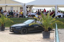 Ein schwarzes Mercedes-Benz Cabrio steht am Rand des Sandplatzes beim Reitturnier in Immenrode, flankiert von zwei Palmen im Topf. Im Hintergrund sitzen Zuschauer unter weißen Eventzelten an Tischen. (Foto: Autohaus Peter)