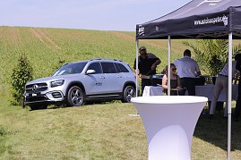 Ein silberner Mercedes-Benz SUV steht auf einer grünen Wiese neben einem schwarzen Pavillon des Autohauses Peter. Unter dem Zelt servieren Mitarbeiter Speisen an die Besucher des Reitturniers in Immenrode. (Foto: Autohaus Peter)