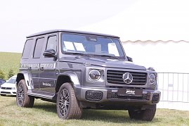 Ein grauer Mercedes-Benz G-Klasse Geländewagen mit der Aufschrift The G-Klass Electrified steht auf einer grünen Wiese beim Reitturnier in Immenrode. Im Hintergrund sind ein weißes Zelt und Absperrgitter zu sehen.[Mercedes-Benz G 580 mit EQ Technologie | Energieverbrauch kombiniert: 30,3-;27,7 kWh/100 km | CO2-Emissionen kombiniert: 0 g/km | CO2-Klasse: A] (Foto: Autohaus Peter)