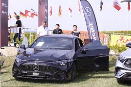 Ein schwarzes Mercedes-Benz Fahrzeug steht mit geöffneter Fahrertür auf der Ausstellungsfläche beim Reitturnier in Immenrode. Dahinter stehen drei Erwachsene, im Hintergrund sind Fahnen, Absperrgitter und ein Werbebanner des Autohauses Peter zu sehen. (Foto: Autohaus Peter)