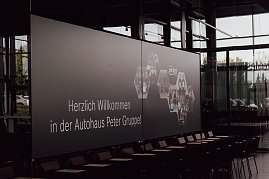 Leinwand mit der Begrüßung Herzlich willkommen in der Autohaus Peter Gruppe! in der Firmenzentrale in Nordhausen. Auf der Leinwand sind auch Fotos von Mitarbeitern und Azubis zu sehen. (Foto: Autohaus Peter)