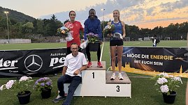 Drei Athlet:innen stehen auf dem Siegerpodest mit Blumen in den Händen, vor ihnen Mercedes-Benz Pkw Verkaufsleiter Jörn Bierwisch mit weißem Shirt. Hinter dem Podest Sponsorenbanner und Abendhimmel. (Foto: Autohaus Peter)