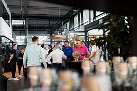 Mehrere Menschen stehen und unterhalten sich in der Eingangshalle des Autohauses. Im Hintergrund sind Glasfassaden und Pflanzen sichtbar. (Foto: Buchardt | Autohaus Peter)