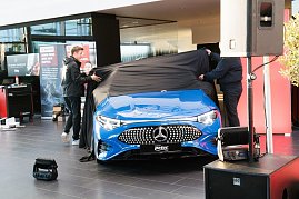 Ein blauer Mercedes CLA wird auf der Bühne präsentiert. Zwei Männer ziehen ein schwarzes Tuch von der Motorhaube. (Foto: Buchardt | Autohaus Peter )