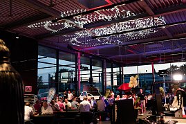 Viele Gäste sitzen an langen Tischen in der beleuchteten Eventhalle. An der Decke sind dekorative Lichtinstallationen angebracht. (Foto: Buchardt | Autohaus Peter )