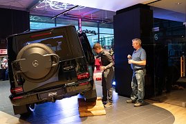 Ein schwarzer Mercedes-Geländewagen steht schräg auf einer Holzrampe, um seine Geländefähigkeit zu demonstrieren. Zwei Männer betrachten das Auto aus nächster Nähe. (Foto: Buchardt | Autohaus Peter )