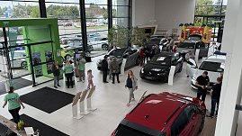 „Blick von oben in den Ausstellungsraum des Autohauses Autowelt Peter während der Jubiläumsfeier zu 130 Jahren koda. Besucherinnen und Besucher schauen sich verschiedene Fahrzeuge an, Mitarbeitende in grünen Shirts beraten. Im Hintergrund steht eine bunte Hüpfburg für Kinder. (Foto: Autohaus Peter)