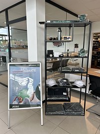 Vitrine mit koda-Merchandising-Artikeln wie Mützen, Flaschen und Accessoires im Autohaus Autowelt Peter. Daneben ein Aufsteller mit der Aufschrift Lets Celebrate  Aktionspreise. (Foto: Autohaus Peter)
