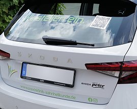 Das Heck eines weißen koda-Fahrzeugs mit der Aufschrift „Wir stellen ein.“ und einem QR-Code auf der Heckscheibe. Darunter ist das Logo der Klinik zu sehen. (Foto: Autohaus Peter)