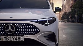 Das Bild zeigt einen wei&szlig;en Mercedes-Benz CLA Shooting Brake, der auf einer breiten, nahezu leeren Stadtstra&szlig;e f&auml;hrt. Moderne Geb&auml;ude umgeben die Szene, das Licht wirkt weich und fr&uuml;hmorgendlich. Der Wagen ist seitlich zu sehen und vermittelt Dynamik sowie Eleganz.