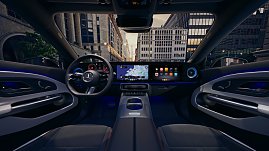 Das Bild zeigt einen wei&szlig;en Mercedes-Benz CLA Shooting Brake, der auf einer breiten, nahezu leeren Stadtstra&szlig;e f&auml;hrt. Moderne Geb&auml;ude umgeben die Szene, das Licht wirkt weich und fr&uuml;hmorgendlich. Der Wagen ist seitlich zu sehen und vermittelt Dynamik sowie Eleganz.