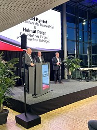 Drei M&auml;nner auf einer B&uuml;hne der Automobil Messe Erfurt, zwei am Rednerpult, einer daneben. Auf der Leinwand stehen ihre Namen.