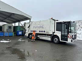 M&uuml;llfahrzeug Garbage Truck of the Future steht an einer Sammelstelle neben Containern.