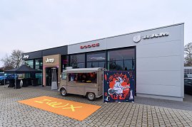 Autohaus mit Jeep-, Dodge- und RAM-Showroom, davor Foodtruck und Eventposter Hex.