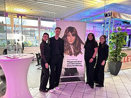 Vier Personen vor LOréal-Stand mit Werbebanner und Eventbeleuchtung.