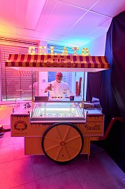 Eisverkäufer an nostalgischem Gelato-Stand mit beleuchteter Beschriftung.
