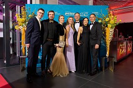 Gruppe elegant gekleideter Gäste vor Sponsorenwand bei Event.