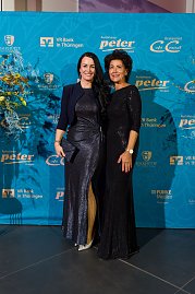 Zwei elegant gekleidete Frauen vor Sponsorenwand bei Event.