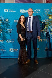 Elegant gekleidetes Paar vor Sponsorenwand bei Event.