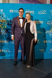 Elegant gekleidetes Paar vor Sponsorenwand bei Event.